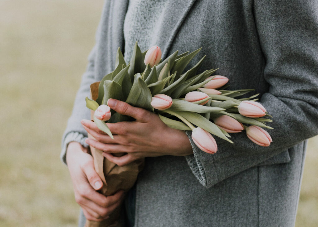 Woman in a gray coat holding a bouquet of tulips