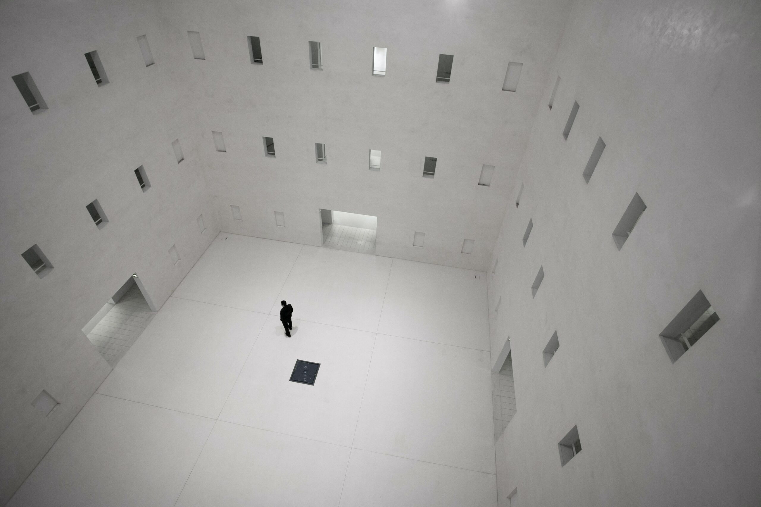 Person in a large white room with two stories of windows and doors