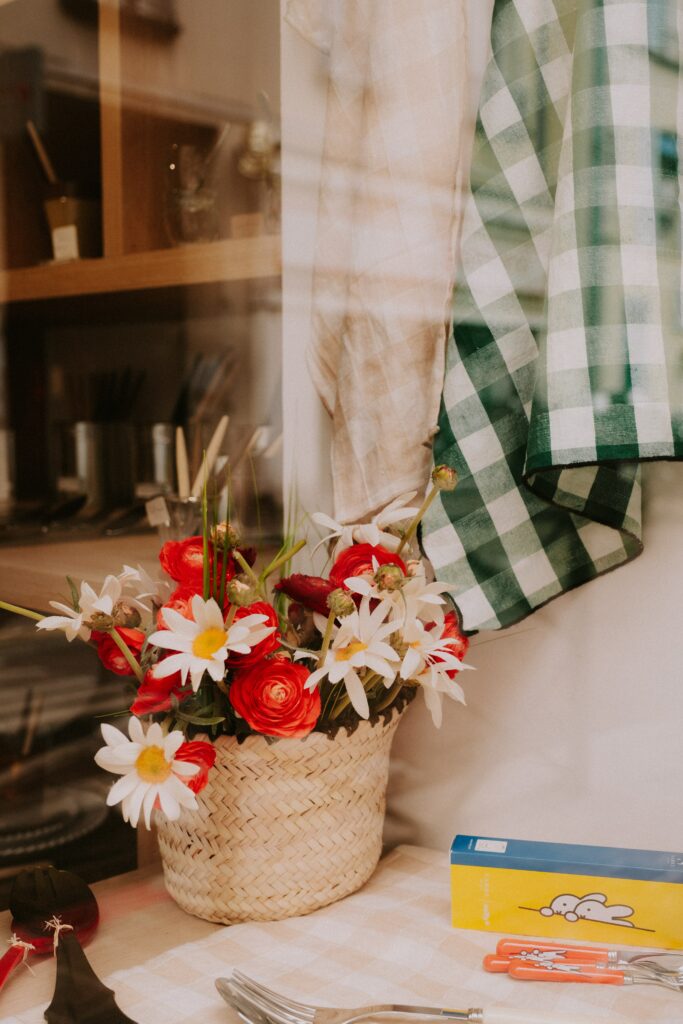 Basket of flowers in window of cafe with green checkered cloth