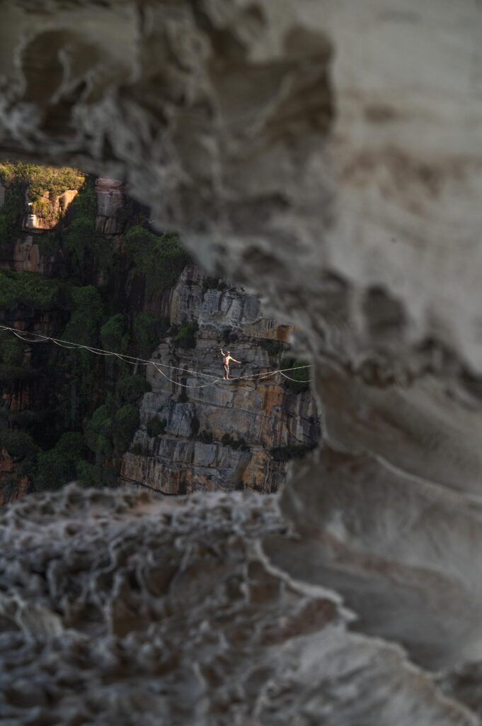 Person walking on a tight rope surrounded by rocks