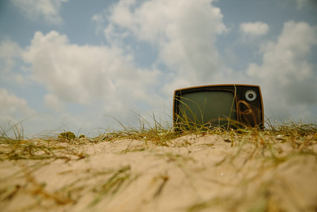 Vintage TV sitting in sand bank in front of a blue sky