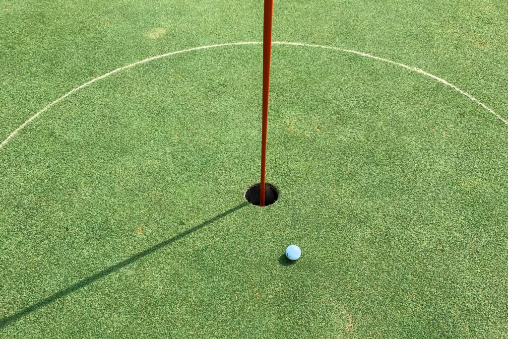 Golf green with golf ball next to hole