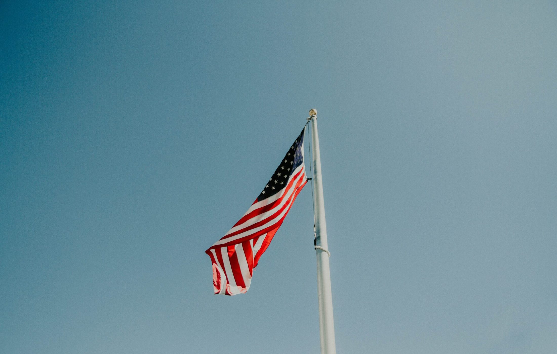 American flag waving in the wind against clear light blue sky